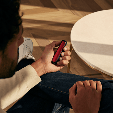 Man holding a Ploom device with Lava Red Front Panel