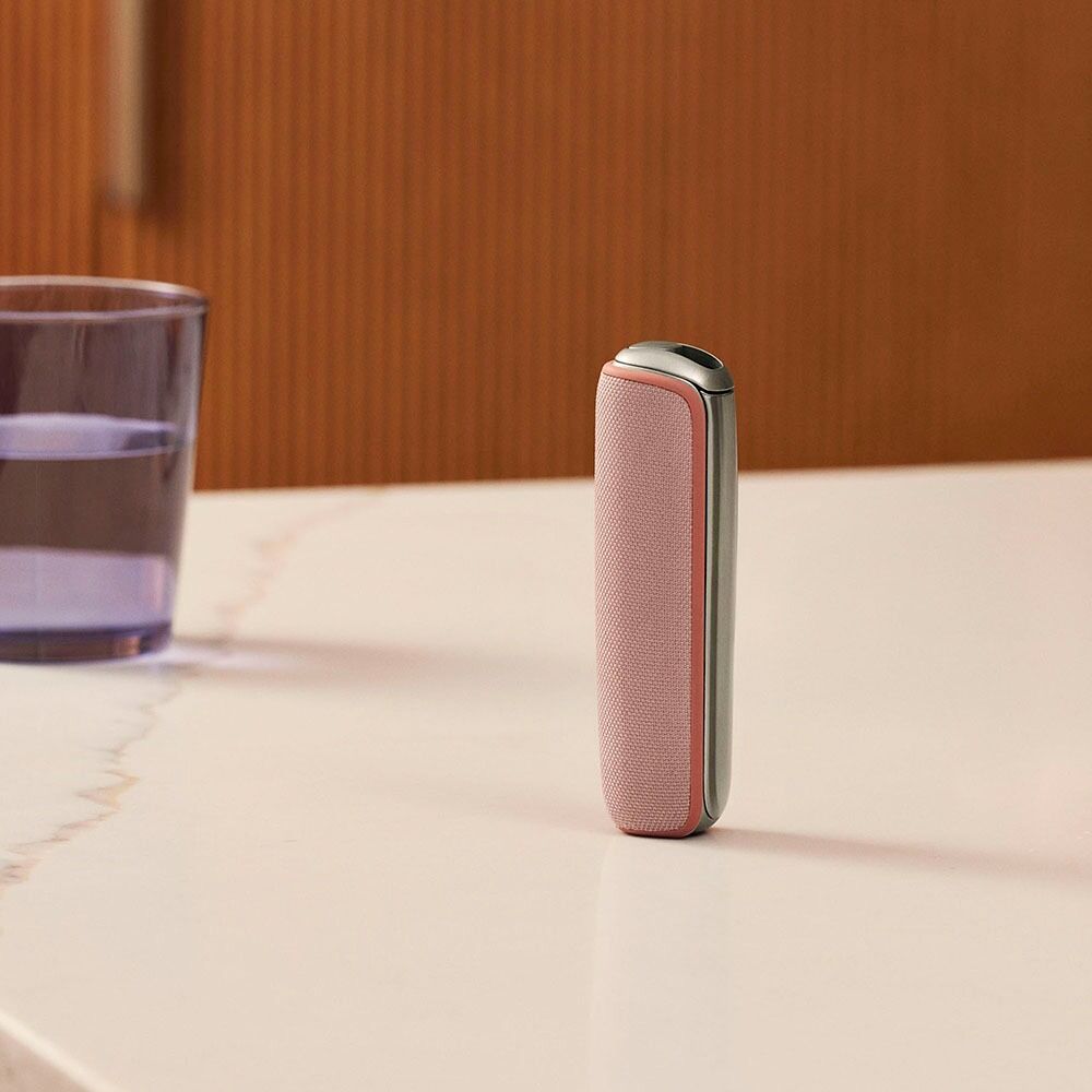 Ploom device with Rose Gold Back Cover standing on a table
